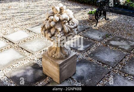 Garden courtyard with elegant cement sculpture, paving and pebbles - seating bench in background Stock Photo