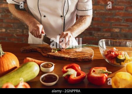 Man cutting a cucumber with a chef's knife. Thin slices of the