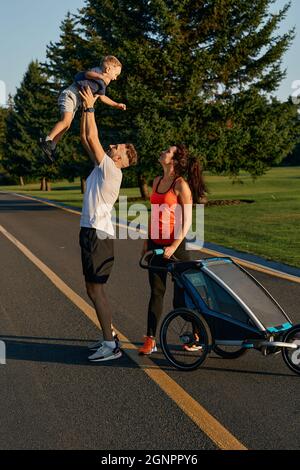 Family having fun outdoors. Father throws up son during leisure with mother, family spend time togetherness, lifestyle Stock Photo