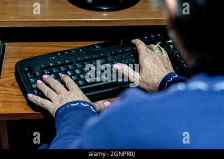 Over-the-shoulder view of a senior female typing on a keyboard Stock Photo