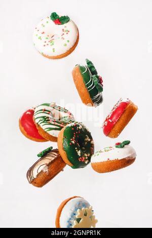 Flying Christmas donuts. Colorful doughnuts with sprinkles falling or flying in motion against white background.  Selective focus Stock Photo