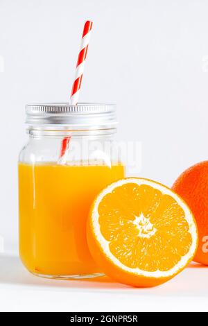 Orange juice in fast food closed cup with tube and slice of orange isolated on white. Glass jar with a tube with freshly squeezed orange juice Stock Photo