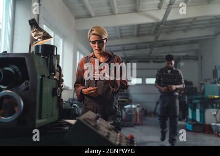 Portrait of young industrial woman working indoors in metal workshop. Stock Photo