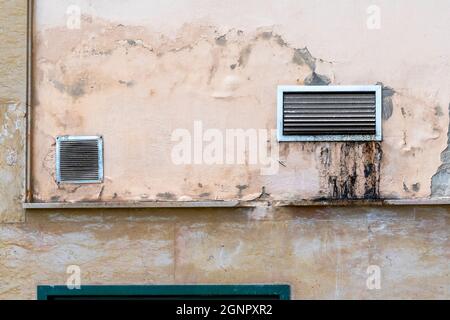 Dirty ventilation grill with drips of industrial grease on the weathered peeling back wall of the cafe. Close up Stock Photo