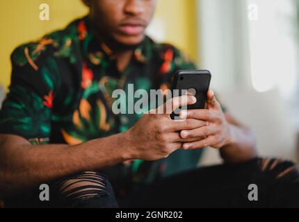 Portrait of unrecognizable young man using smartphone, sitting on sofa at home, social networks concept. Stock Photo