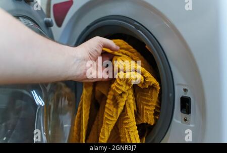 Man loading towel into washing machine. Stock Photo