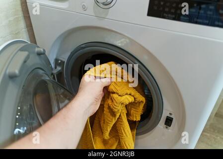 Man loading towel into washing machine. Stock Photo