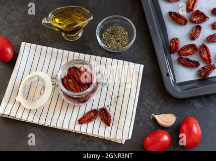 dried tomatoes in glass jar on dark table Stock Photo