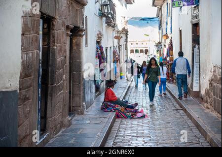 Old Quechua woman traditional clothing sale colorful tablecloths and fabric at street of Cusco City, Peru. Stock Photo