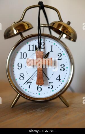 Old-fashioned vintage copper alarm clock with christian cross. Stock Photo