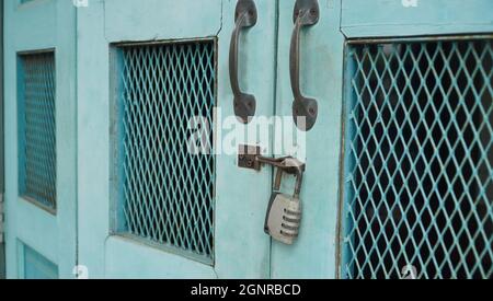 Vintage blue wooden folding door with metal rusted latch and unlocked padlock Stock Photo