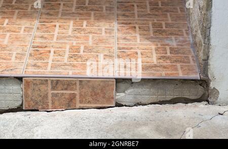 Cracked floor tiles, house damaged with floor subsidence. Stock Photo