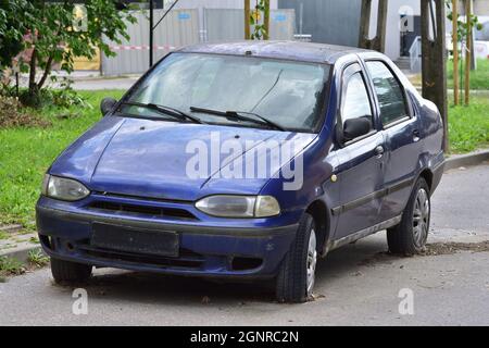 The damaged car is standing on flat tires in the parking lot. Scrap. Stock Photo