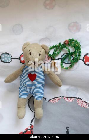Teddy bear with rosary in the room of a child.    Religion at home.  Faith and spirituality. Stock Photo