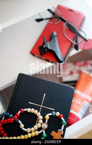 Bible, rosary and glasses on nightstand. Stock Photo