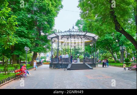 ODESSA, UKRAINE - June 18, 2021: The picturesque City Garden with tall green trees and the lace-like cast iron summer house, on June 18 in Odessa Stock Photo