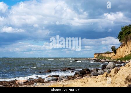 Steep coast with sandy beach and boulders on the Baltic Sea on a summer day with blue sky and clouds Stock Photo