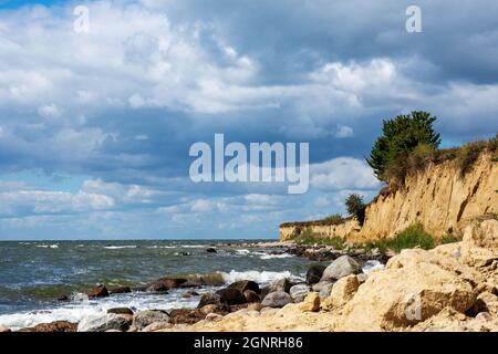 Steep coast with sandy beach and boulders on the Baltic Sea on a summer day with blue sky and clouds Stock Photo