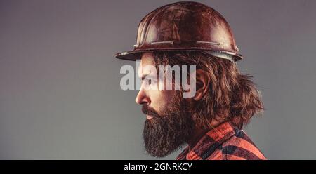 Man builders, industry. Builder in hard hat, foreman or repairman in the helmet. Building, industry, technology - builder concept. Bearded man worker Stock Photo