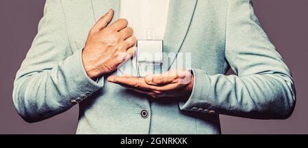 Men perfume in the hand on suit background. Man in formal suit, bottle of perfume, closeup. Fragrance smell. Men perfumes. Fashion cologne bottle. Man Stock Photo