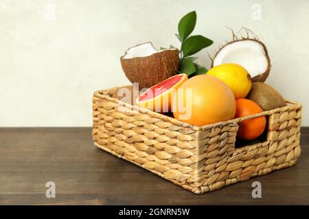 Basket with exotic fruits on wooden table. Stock Photo