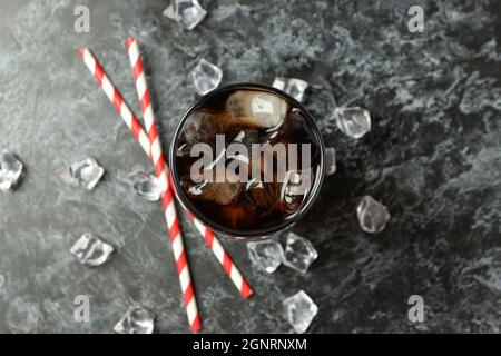 Glass of cola, ice and straws on black smokey background. Stock Photo