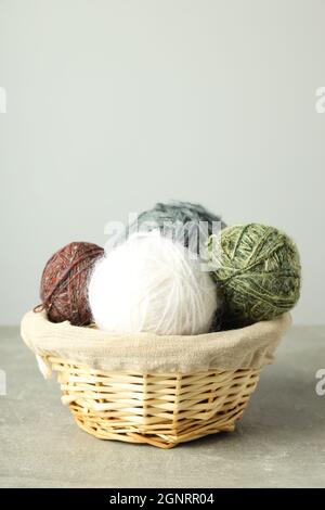 Wicker basket with yarn balls on light gray table Stock Photo