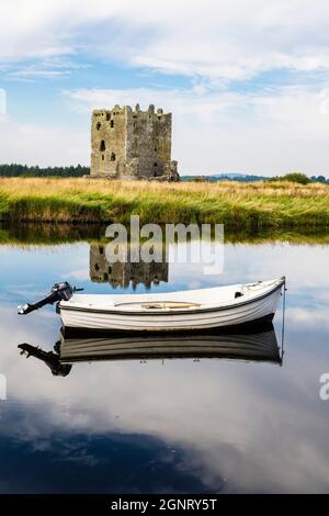 Threave Castle reflected in calm waters of the River Dee with small ferry boat. Threave, Castle Douglas, Dumfries and Galloway, Scotland, UK, Britain Stock Photo