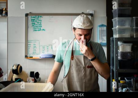 A young man in a cap and apron at the baker's job. Problem solving concept. Stock Photo