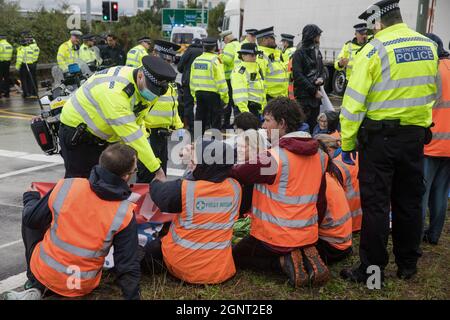Colnbrook, UK. 27th September, 2021. Metropolitan Police officers monitor Insulate Britain climate activists who had previously blocked a slip road from the M25 at Junction 14 close to Heathrow airport and then glued themselves together as part of a campaign intended to push the UK government to make significant legislative change to start lowering emissions. The activists are demanding that the government immediately promises both to fully fund and ensure the insulation of all social housing in Britain by 2025 and to produce within four months a legally binding national plan to fully fund and Stock Photo