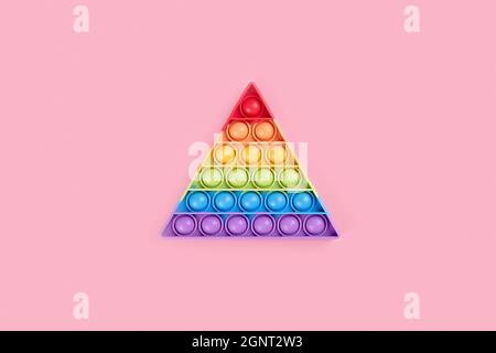 Bright rainbow toy antistress for children and adults on a pink background. Flexible sensory antistress toy pop it triangle shape Stock Photo