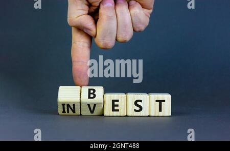 Best invest symbol. Businessman turns wooden cubes and changes the word 'invest' to 'best'. Beautiful grey background. Business and best invest concep Stock Photo