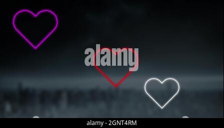 Image of red pink and white neon hearts flashing on dark background Stock Photo