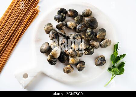 fresh clams on white marble cutting board and whole grain pasta Stock Photo