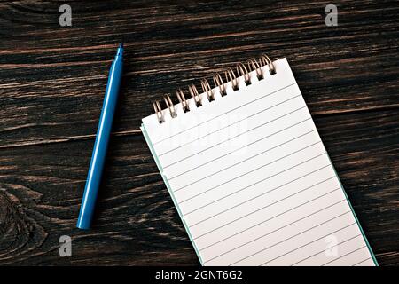 template for text and design. empty white notepad and one marker on old wooden dark background Stock Photo