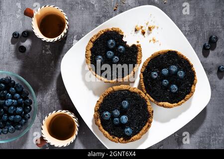 small italian crostata cakes with blueberry jam on a plate and coffee Stock Photo