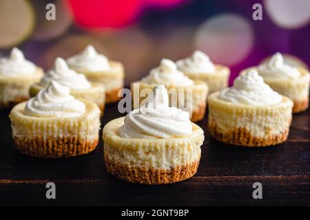 Mini Eggnog Cheesecakes Topped with Whipped Cream: Eggnog cheesecake cupcakes with a Christmas background Stock Photo