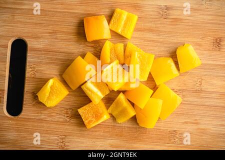 Yellow Bell Pepper Sliced into Large Chunks: Sweet yellow pepper cut into large pieces on a bamboo cutting board Stock Photo