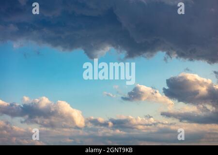 Heavy dark clouds on blue sky background, Sunbeams through the clouds. Fluffy cumulus clouds, cloudscape white and grey color Stock Photo