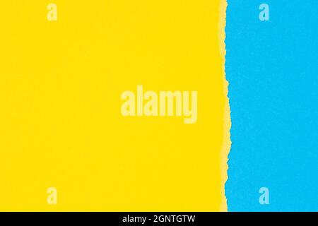 Torn grunge ripped yellow paper on light blue color paper background Stock Photo