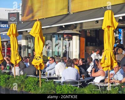 Diners eat, drink and socialize on an outdoor patio in the Viaduct harbor area of Auckland, New Zealand. Stock Photo