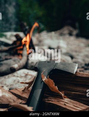axe standing near campfire on the logs Stock Photo