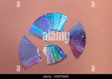 broken retro CD disc with wet drops against brown background Stock Photo