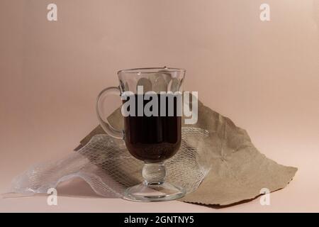 glass of pomegranate juice with torn and wrapping paper against pale pink background Stock Photo