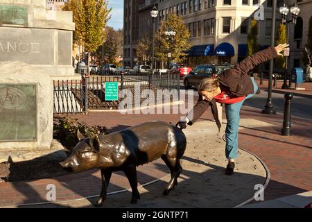 A young man poses with the Pack Square pigs in Asheville, North Carolina. Stock Photo