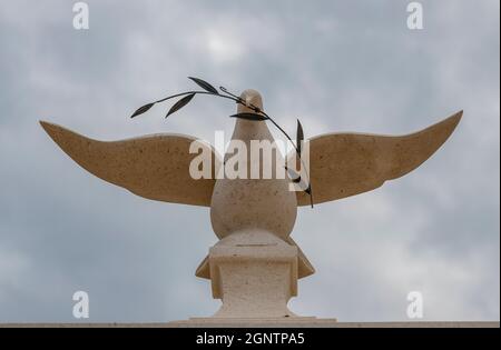 large marble or stone sculpture of a dove or bird carrying an olive branch or twig in its beak on a monument in solomos square zakynthos greece Stock Photo