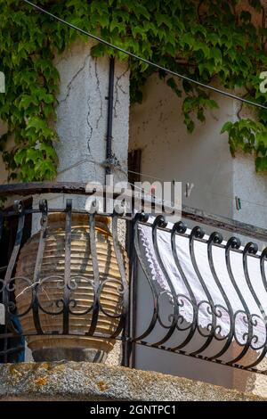 Decorative cast or wrought iron railings on a typically Greek balcony with large terracotta plant pot for decoration. Large olive jar on a balcony . Stock Photo