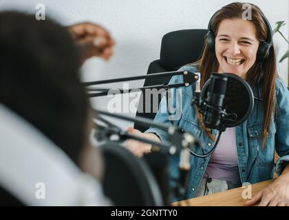 Happy woman recording podcast with crop black man Stock Photo