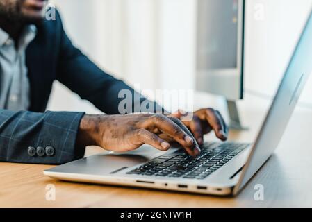Crop black businessman typing on laptop Stock Photo