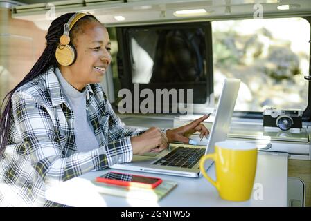 Smiling black traveler working on netbook in van Stock Photo